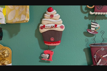 Video of cupcake shaped clock on wall, with mixer shaped pendulum swinging underneath.